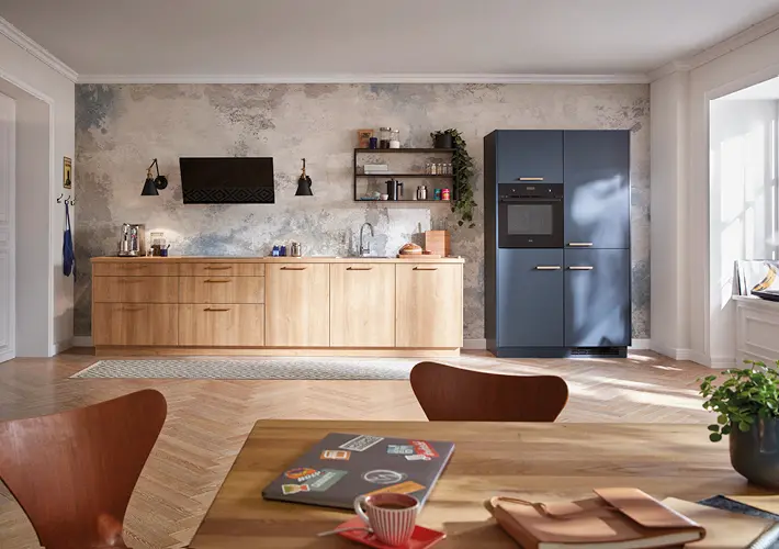 Küchenzeile mit Holzfronten, dunklem Hochschrank, Wandregal und Tisch im Vordergrund